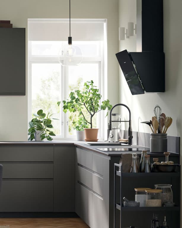 Moderne kleine IKEA Küchenlösung mit Steinender Arbeitsplatte, dunkel grauen Ober - und Unterschränken. daneben ein schiebe Wagerl mit Gewürzen. Auf der Arbeitsplatte sind auch noch drei Dekopflanzen zu sehen.