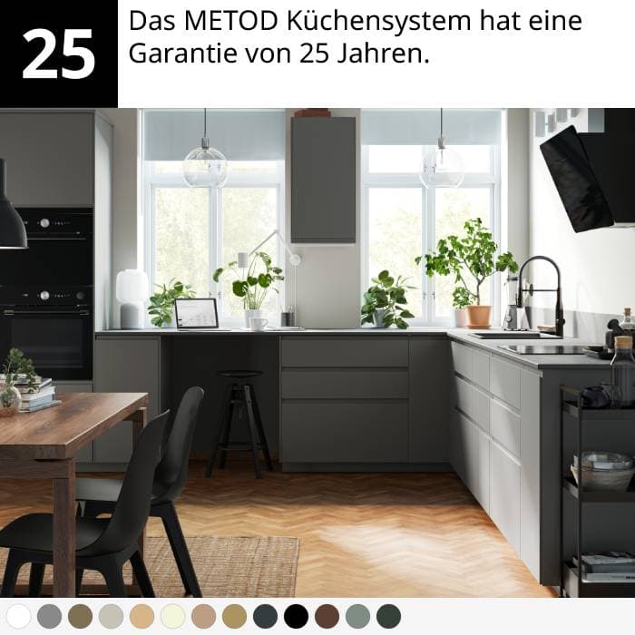 Moderne Küche mit grauen Schränken, Holztisch, schwarzen Stühlen, Pflanzen und Fischgrätboden.