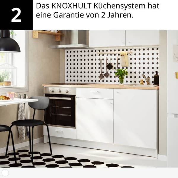 Moderne Küche mit weissen Schränken, Holzarbeitsplatte, Ofen, Punktmuster, Pflanzen und Teppich.