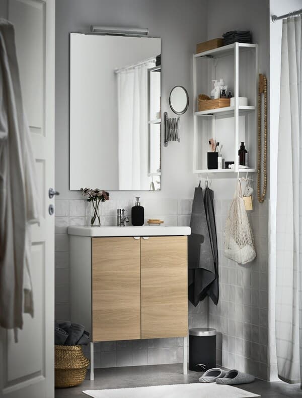 Modernes Badezimmer mit einem großen Wandspiegel, einem kleinen weissen Wandregal sowie einem Waschbeckenunterschrank mit Holzfront.