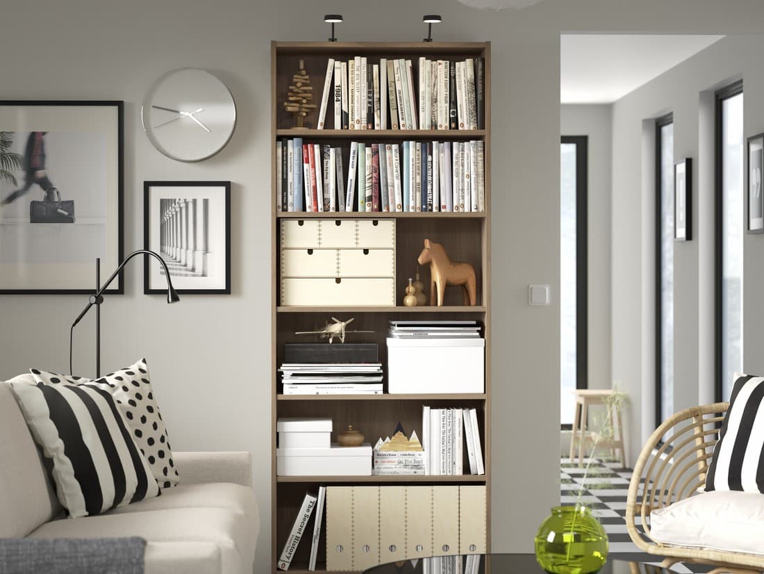 Modernes IKEA-Wohnzimmer mit hohem Bücherregal, gefüllt mit Büchern, Boxen und Dekoration – skandinavisches Design und clevere Aufbewahrungslösung für kleine Räume.


