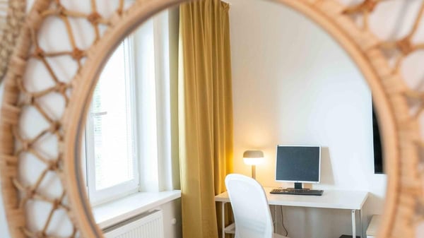 Moderní kancelářský kout v útulném interiéru s dřevěným zrcadlem, bílým stolem a židlí, ideální pro home office nebo studium. Minimalistický design, prosvětlený prostor.