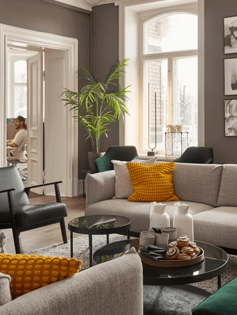 Modernt vardagsrum med grå soffa, gula kuddar, svarta fåtöljer, runda soffbord och stora fönster med naturligt ljus.