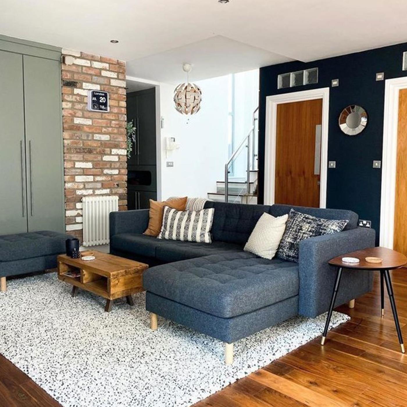 Mörkgrå LANDSKRONA soffa med schäslong stående vid tegelvägg. 