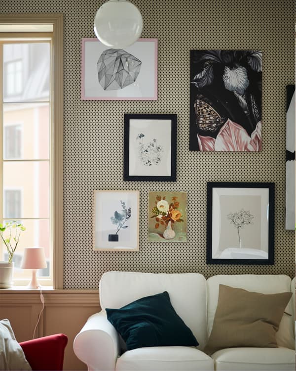 Molduras em velatura preta combinadas com outras molduras para criar uma parede de imagens atrás de um sofá EKTORP branco.