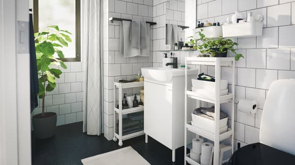 モノクロのモダンなバスルーム。複数の省スペース型収納ユニット、ボックス、屋内用観葉植物が置いてある。
