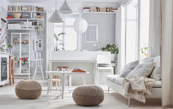 Monolocale arredato con colori chiari: letto, divano, piccola cucina, mobili di vario tipo e due pouf SANDARED.