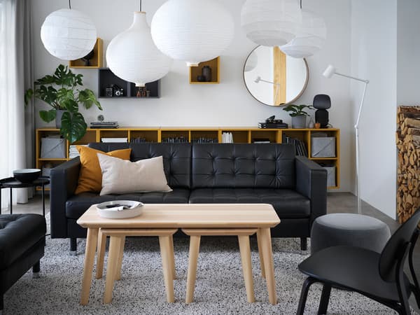 モノトーンのモダンリビング。黒いソファと木製テーブル、観葉植物でシンプルかつ洗練された雰囲気。
