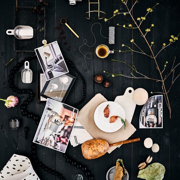 Moodboard con piatto OFTAST bianco, tessile bianco con motivo screziato nero, un espresso e delle foglie su sfondo in legno nero.