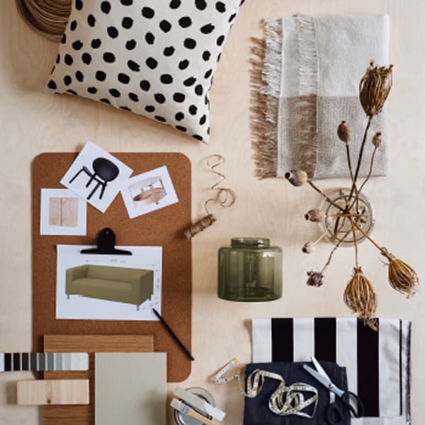 Moodboard met foto's van meubels ligt op een kurken SUSIG onderlegger naast een kussen, twee glazen en kleurstalen.