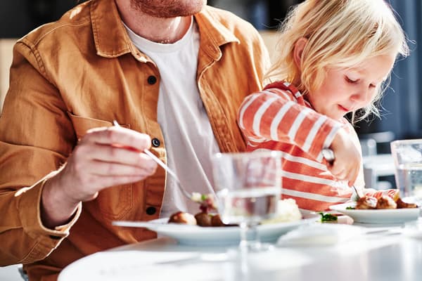 Moški in otrok jesta mesne kroglice v Švedski restavraciji