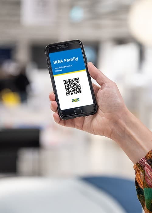 Moteris laiko telefoną su jame esančia IKEA Family kortele