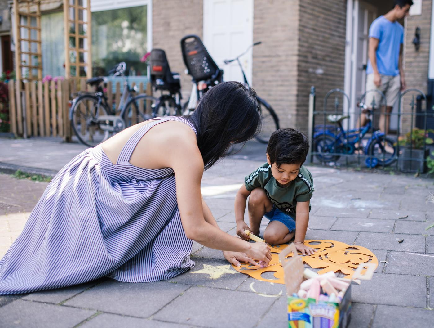 Mother and young son create chalk art on their patio.