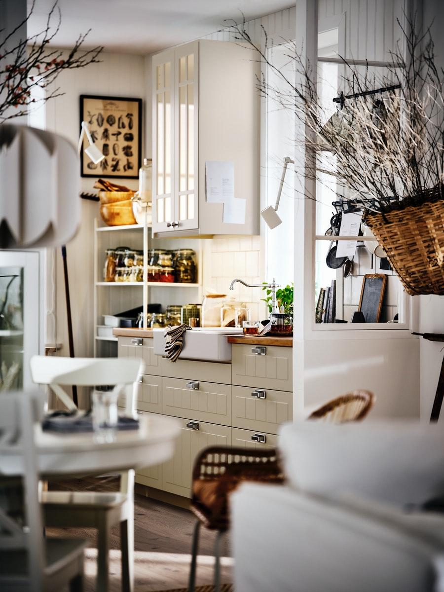 مطبخ مستوحى من الطراز الريفي به واجهات STENSUND بيج على خزائن METOD وحوض HAVSEN أبيض ووحدة رفوف عليها مرطبانات.