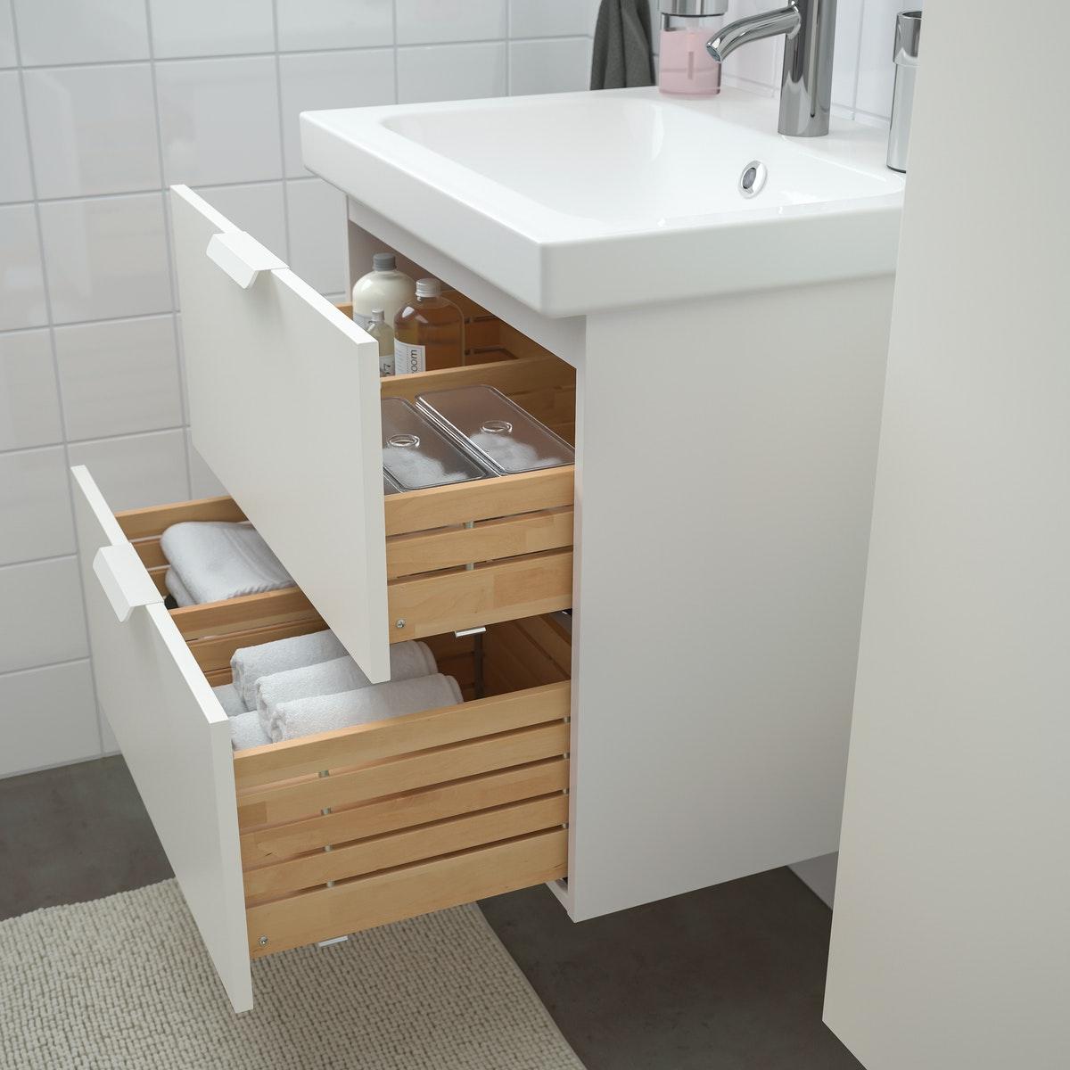 Mueble de baño blanco con madera ODENSVIK  con sus dos cajones abiertos. Se ve que organiza los utensilios de aseo personal en diferentes divisiones.