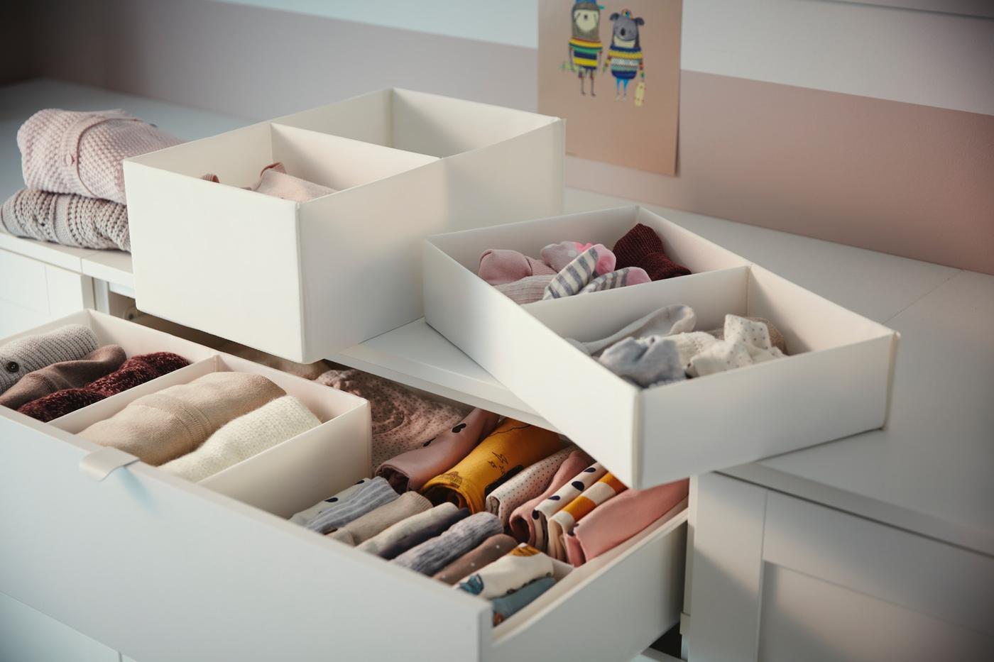 Mueble de organización de ropa blanco RASSLA con ropa interior, poleras y calcetines doblados. 