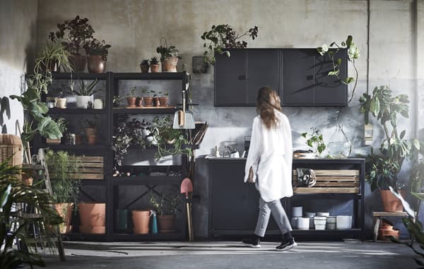 Mueble negro GRILLSKÄR donde se ponen muchos maceteros con plantas y cosas de jardinería. 
