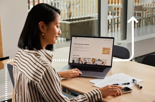 Mujer con un portátil haciendo cálculos con una calculadora.
