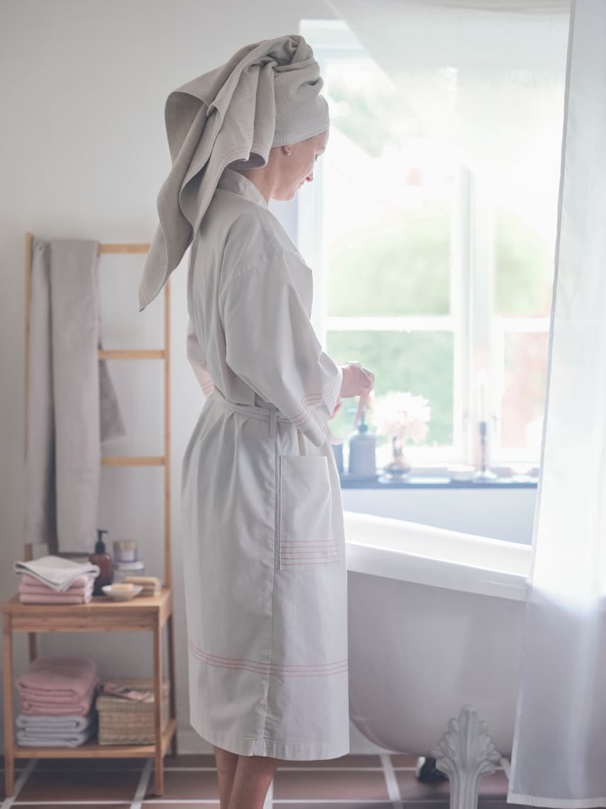 Mujer con una bata de color blanco y una toalla en el pelo.