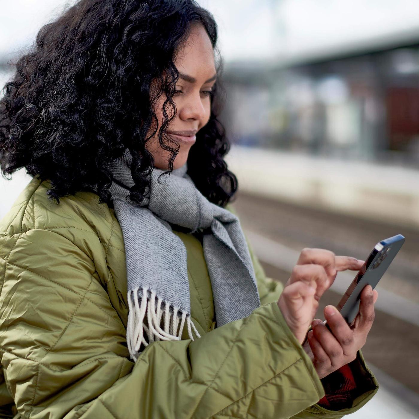 Mujer en el telefono esperando a el tren viendo el app de IKEA
