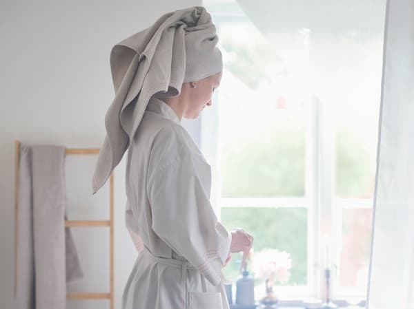 Mujer en un baño con una bata de color blanco y una toalla en la cabeza.