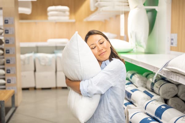 Mujer en una tienda IKEA abrazando una almohada.
