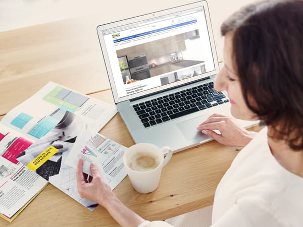 Mujer navegando el sitio web IKEA Chile mientras toma un café y lee artículos.