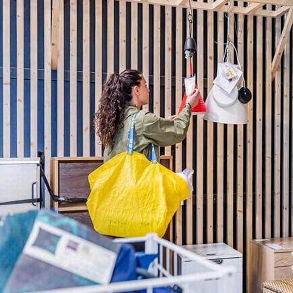 Mujer que lleva una bolsa de compras IKEA amarilla buscando artículos a la venta en el departamento As-is.