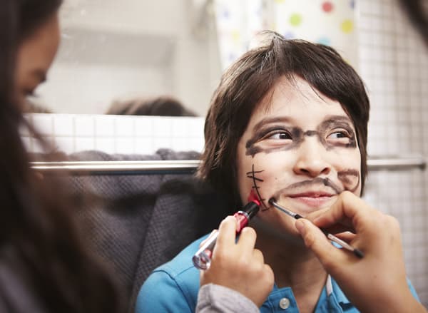 Muka seorang budak lelaki dilukis oleh dua orang rakannya.