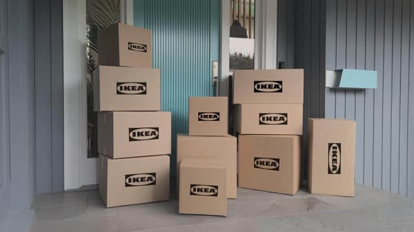 Multiple brown shipping boxes on a front porch with the IKEA logo on them.
