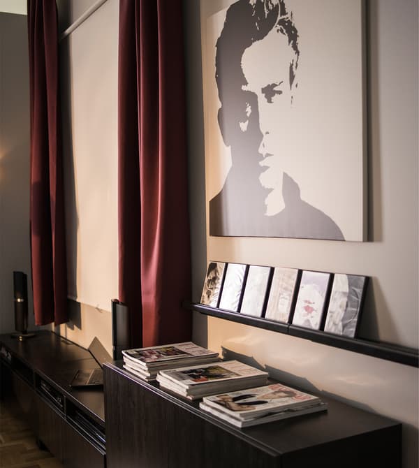 Mur avec écran de projection, œuvre d'art et étagère à photos servant de présentoir à des films.