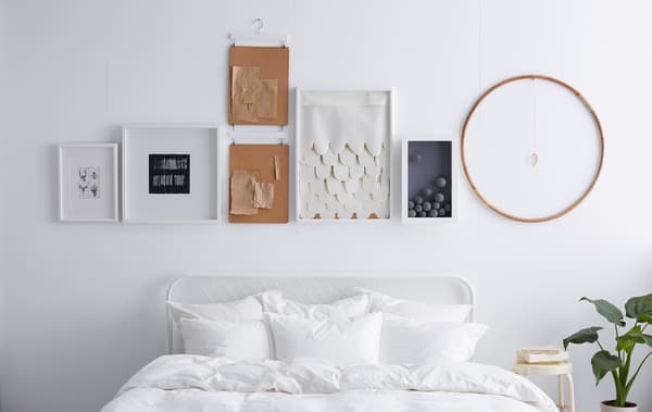 Mur blanc décoré de cadres, avec objets accrochés au-dessus, parfaitement alignés.