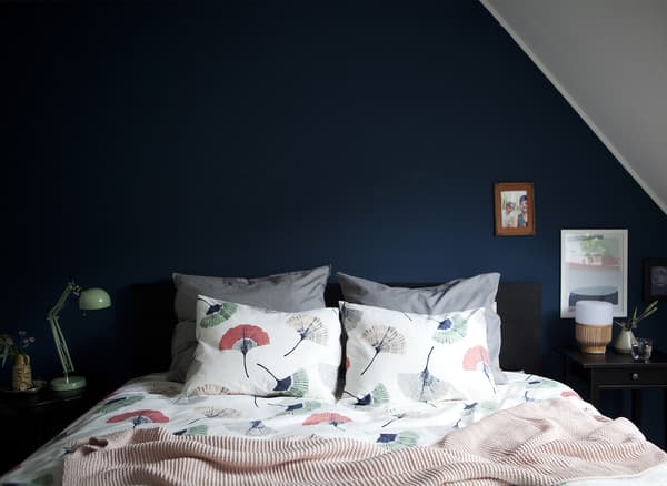 Mur de chambre à coucher bleu foncé et linge de lit coordonné.