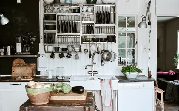 Mur de cuisine avec des panneaux en bois patiné et de la peinture pour tableau noir, avec des étagères ouvertes de style industriel remplies de vaisselle.