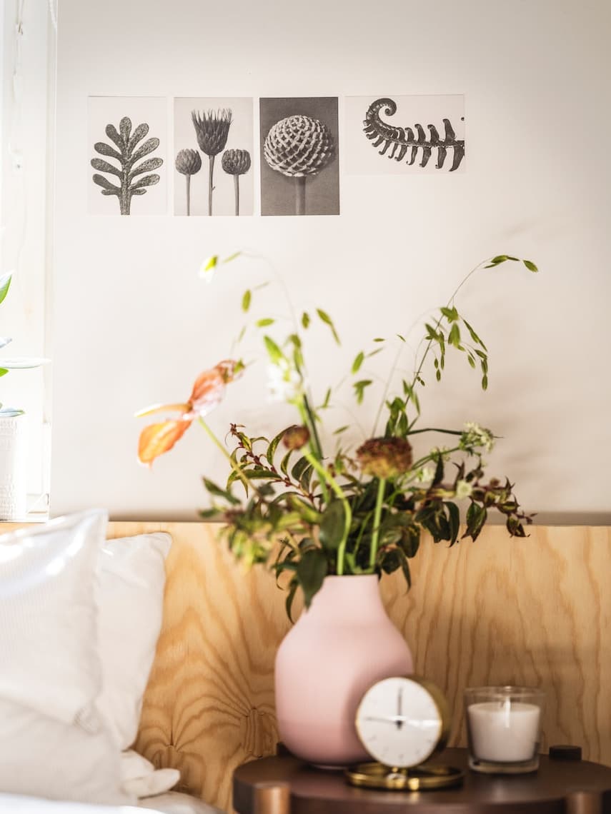 Muralla con una combinación de color blanco y madera, florero de color rosado sobre una mesa auxiliar.
