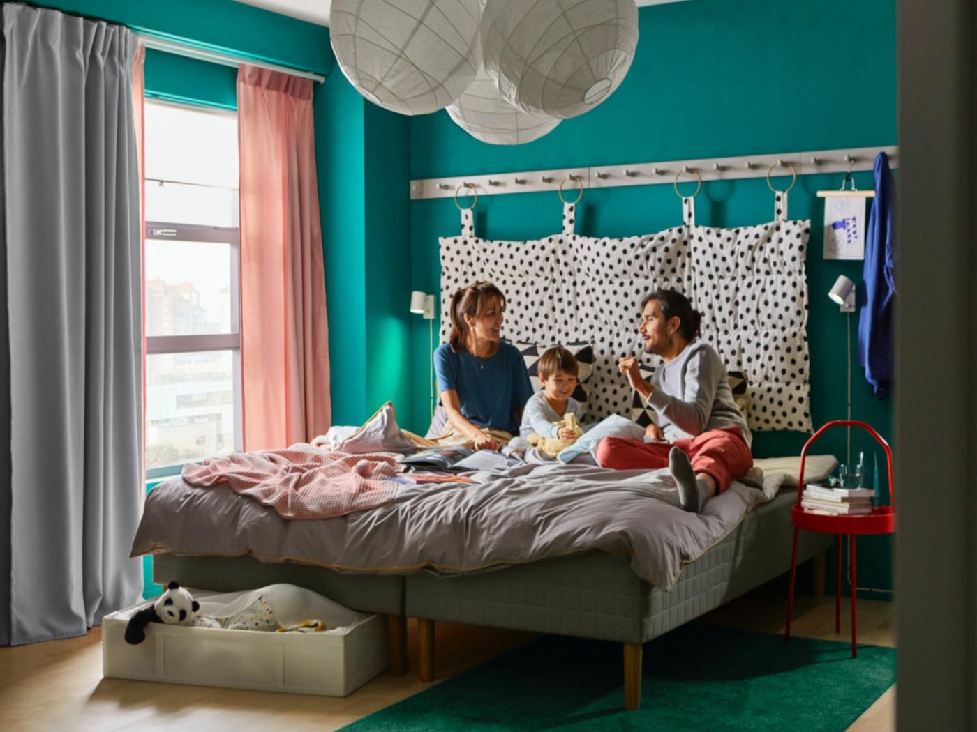 Mutter, Vater und Kind liegen im Elternbett und verbringen gemeinsam Zeit.