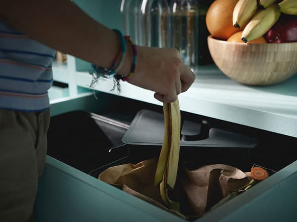 Muž recyklující banánovou slupku v recyklačním systému VARIERA.