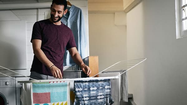 Muž vešia tričká a uteráky v pivnici na sušiak IKEA MULIG.