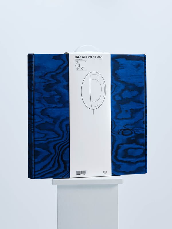 Na bílém podstavci je modrá krabice s nástěnnou lampou z kolekce IKEA ART EVENT 2021 od Sabine Marcelis.