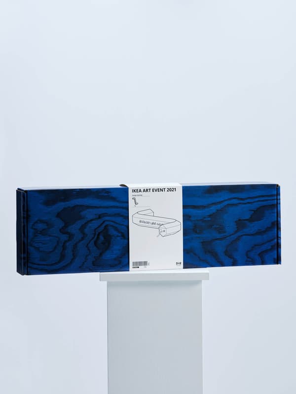 Na bílém podstavci je modrá krabice se stolní lampou LED ve tvaru imbusového klíče z kolekce IKEA ART EVENT 2021 od kreativního týmu Gelchop.