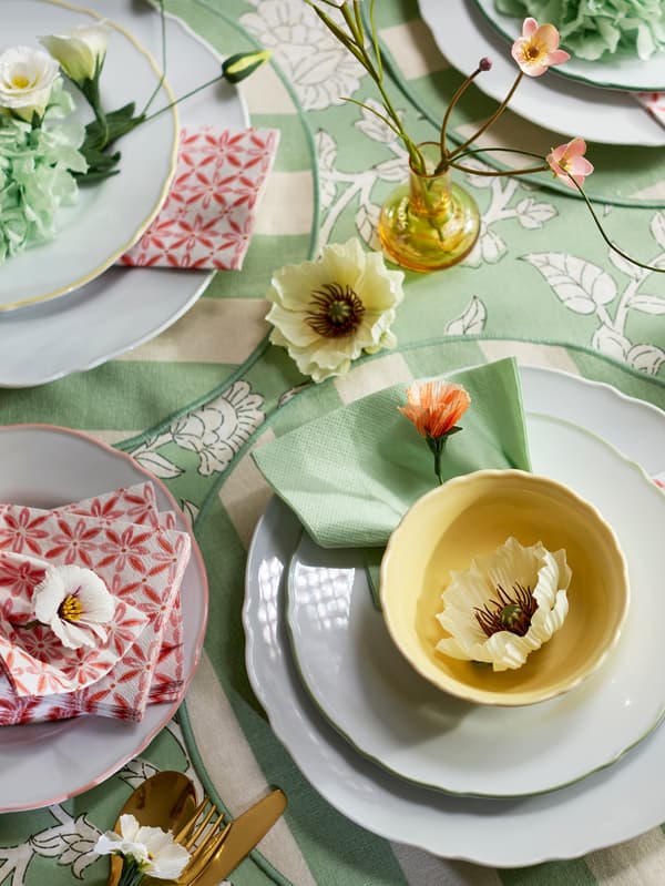 Na jarne prestretom stole leží svetlozelený obrúsok FANTASTISK pri svetložltej miske UPPLAGA na bielych tanieroch UPPLAGA.