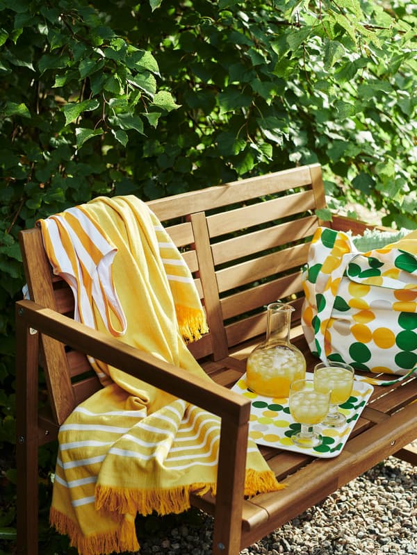 Na lavici s opierkami NÄMMARÖ je podnos s karafou a pohármi BRÖGGAN.