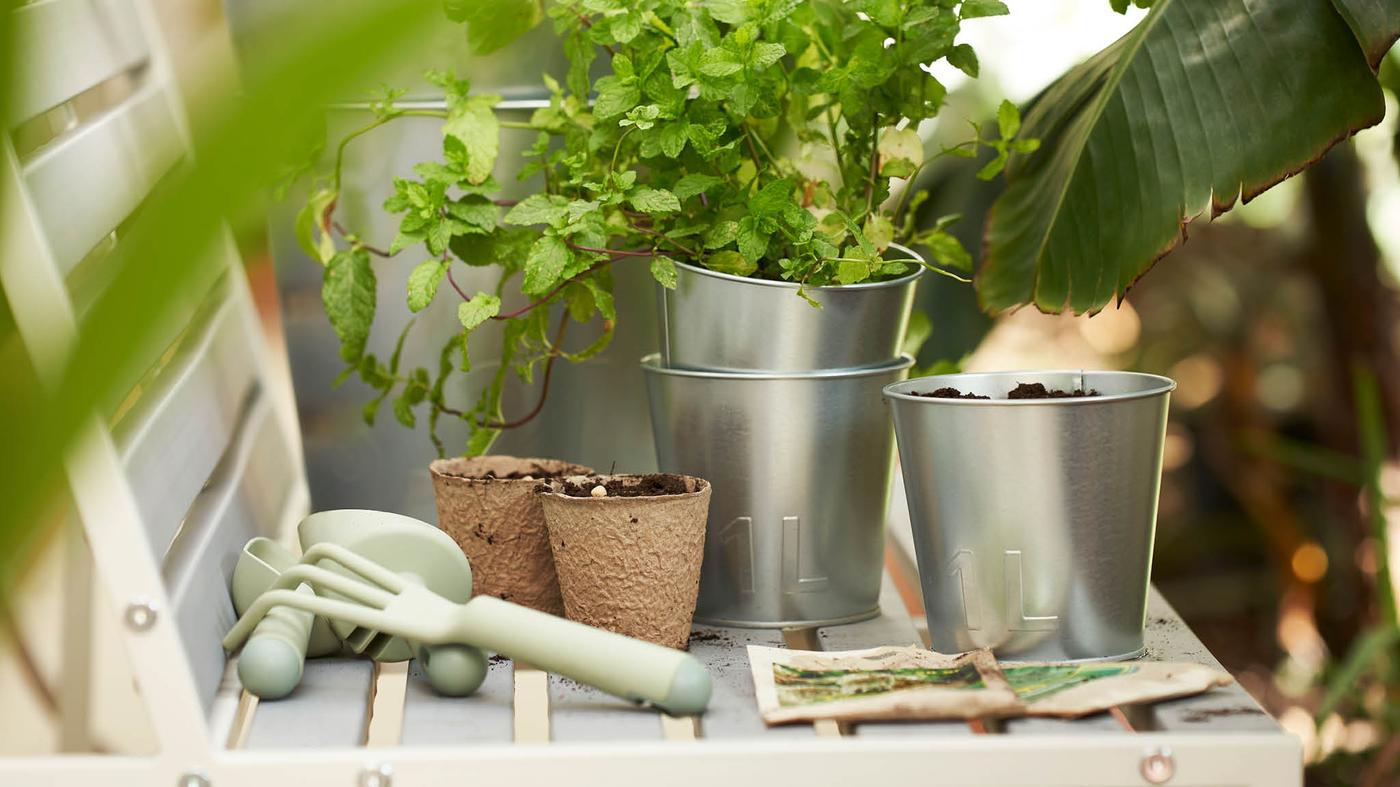 Na lavičke je niekoľko kvetináčov ÅKERBÄR a súprava zeleného záhradníckeho náčinia GRÄSMARÖ.