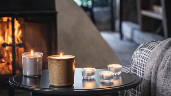 Na odkládacím stolku stojí svíčky z řady ENSTAKA. Dotváří atmosféru tmavého interiéru s krbem.