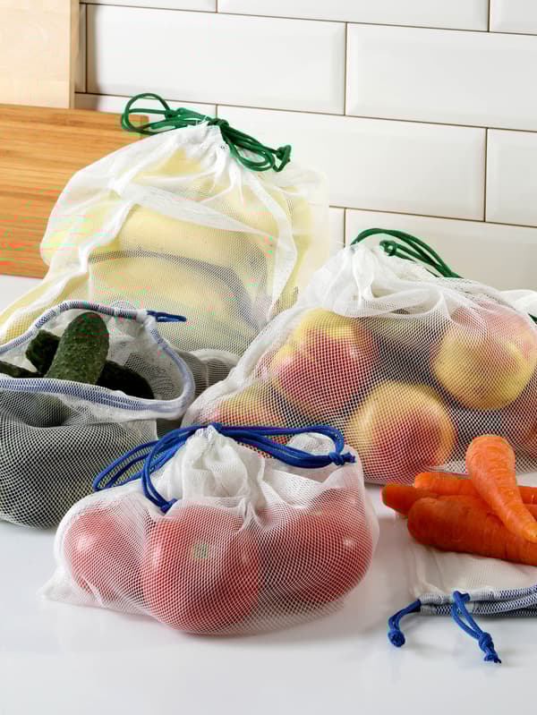 Na pracovnej doske sú vrecká na potraviny LAKAMARK s mrkvou, uhorkami, jablkami, banánmi a paradajkami.