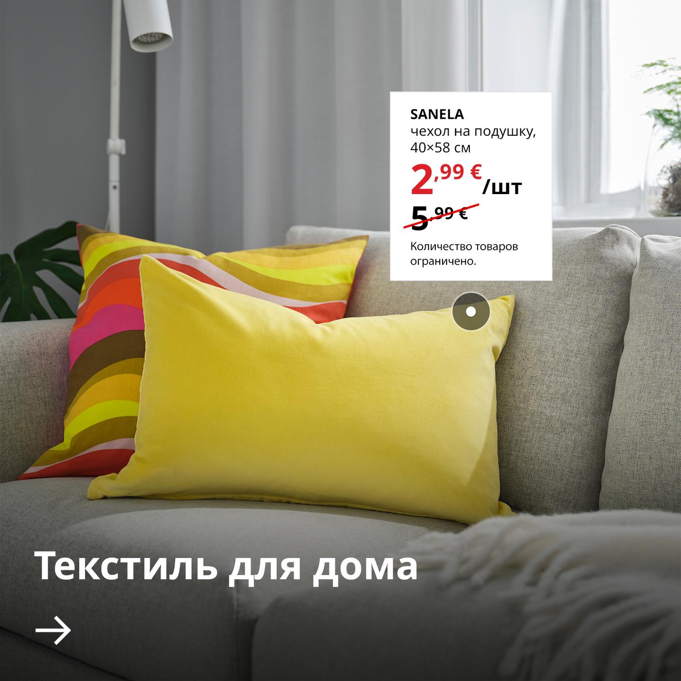 На сером диване лежат две подушки в жёлтом и разноцветном чехлах. Рядом на белом фоне указана цена по акции на жёлтый чехол SANELA — 2,99 € (обычная цена 5,99 €). Ниже расположена стрелка с текстом «Домашний текстиль».