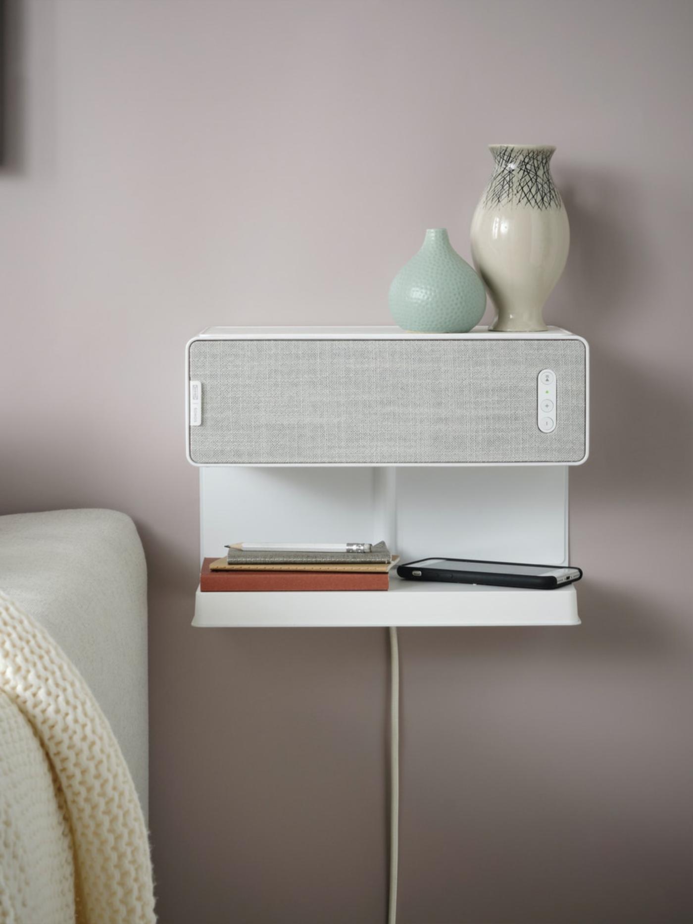 Na stene je pripevnený reproduktor s policou a vázami na ňom.