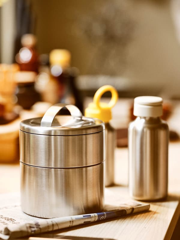 Na stole je dvojposchodová termoska FÖRSKAFFA, vedľa stojí fľaša na vodu ENKELSPÅRIG.