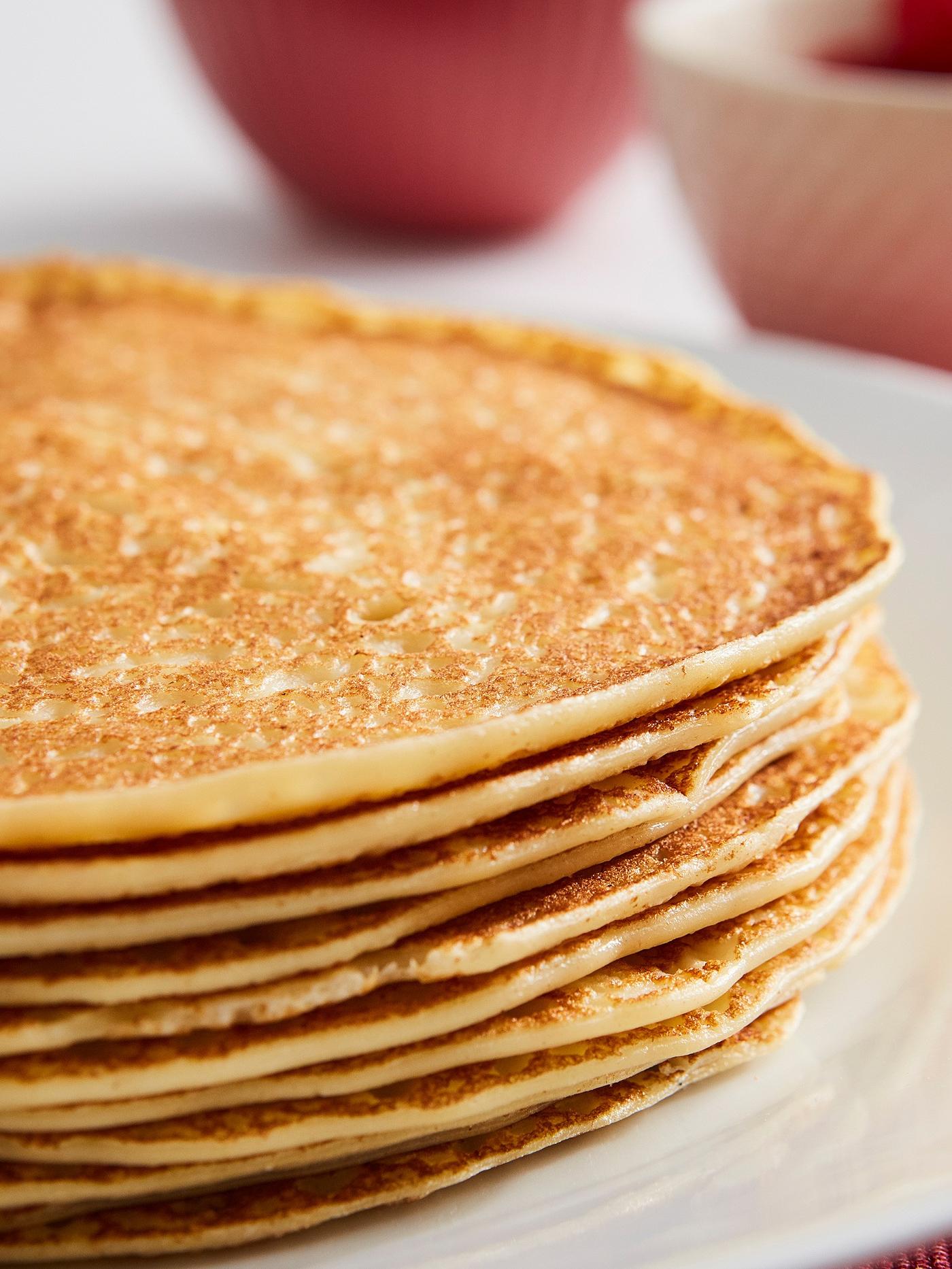 Na talíři leží palačinky naskládané jedna na druhou v úhledné hromádce.