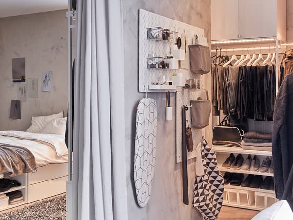 Na wąskiej ścianie wisi tablica perforowana SKÅDIS z akcesoriami, przechowując i organizując artykuły do pielęgnacji ubrań.